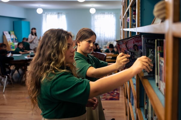 students reaching for books in library